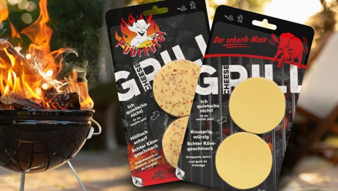 Abgepackter Grillkäse der Käserei Studer mit loderndem Feuer in einer Feuerschale im Hintergrund.