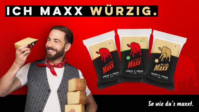 Markengesicht hält Der scharfe Maxx in der Hand und zeigt auch Der edle Maxx