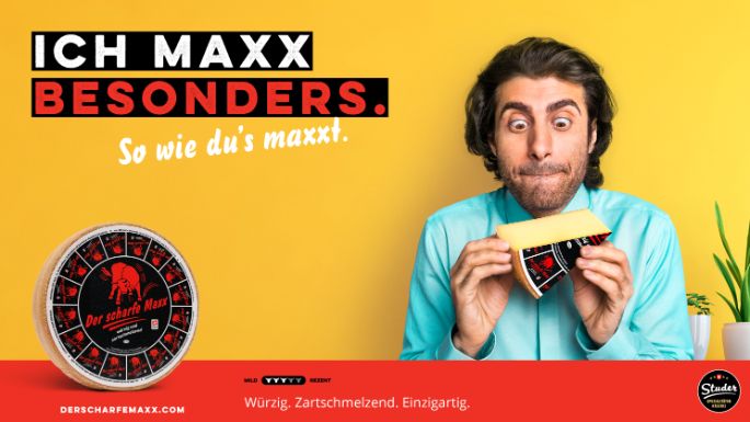 Werbesujet für «Der scharfe Maxx». Junger Mann mit türkisem Hemd hält Käsestück in den Händen.