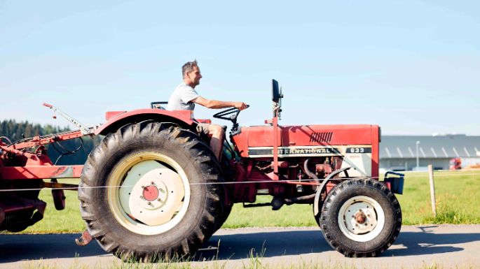 Milchbauer beim Fahren mit rotem Traktor